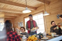 Friends serving and eating food in cabin — Stock Photo
