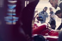 Manager and formula one race car driver talking in repair garage — Stock Photo