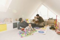 Родители-геи играют с маленькими сыновьями в игровой комнате — стоковое фото