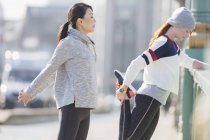 Жінки бігуни тягнуться на сонячному тротуарі — стокове фото