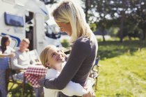 Affectionate mother and daughter hugging outside sunny motor home — Stock Photo