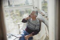 Senior man talking on cell phone on sun porch — Stock Photo