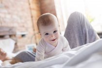 Portrait smiling baby girl laying on bed with mother — Stock Photo