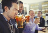Hombre bebiendo cerveza con amigos en el bar - foto de stock