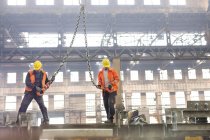 Steel workers with crane hooks in factory — Stock Photo
