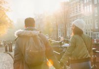 Young couple holding hands walking on sunny urban autumn street, Amsterdam — Stock Photo