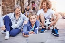 Friends with soccer ball hanging out using laptop — Stock Photo