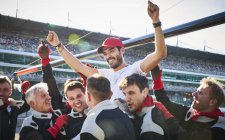 Formula one racing team carrying driver on shoulders, celebrating victory — Stock Photo