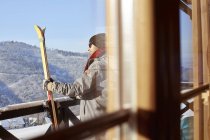 Sciatore maschile con sci sul balcone soleggiato della cabina — Foto stock
