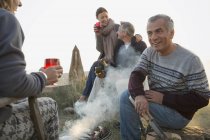 Mature couples drinking wine and barbecuing on beach — Stock Photo