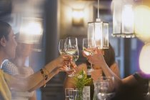 Freundinnen stoßen Weißweingläser am Restauranttisch an — Stockfoto
