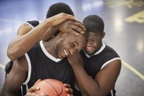 Jugadores de baloncesto jóvenes y felices abrazando y celebrando después de la victoria - foto de stock