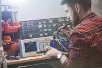 Инженер-мужчина, собирающий электронику, с помощью паяльника — стоковое фото