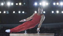 Male gymnast performing on pommel horse in arena — Stock Photo