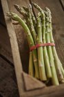 Still life close up fresh, organic, green, healthy asparagus bunch in wood crate — Stock Photo