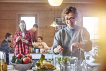 Woman tossing salad for friends in cabin — Stock Photo