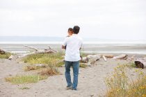 Батько, що носить сина на покинутому пляжі — стокове фото