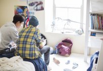 Two teenage boys sitting on bed in messy room — Stock Photo