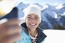 Усміхнена жінка бере селфі в снігу — стокове фото