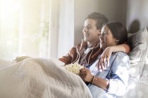 Teenage couple lying in bed and watching tv — Stock Photo