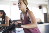 Determined young woman using elliptical bike in gym — Stock Photo