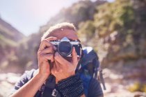 Young man hiking, photographing with camera — Stock Photo