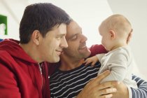 Ласковые родители-геи обнимают маленького сына — стоковое фото