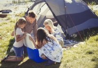 Family opening cooler outside sunny campsite tent — Stock Photo