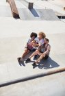 Vista aérea amigos masculinos tomando selfie con el teléfono de la cámara en el parque de skate soleado - foto de stock
