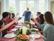 Großvater stößt am Weihnachtstisch mit Wein an — Stockfoto