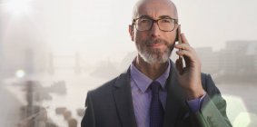 Portrait serious businessman talking on cell phone on urban bridge, London, UK — Stock Photo