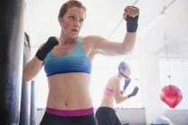 Решительная, жесткая женщина боксер теневой бокс в тренажерном зале — стоковое фото