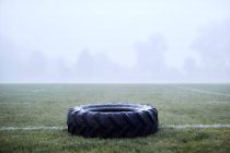 Rubber tire on foggy football field — Stock Photo