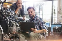Motorradmechaniker mit Laptop in Werkstatt — Stockfoto