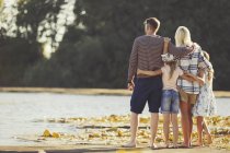 Familie kuschelt sich am sonnigen Seeufer — Stockfoto
