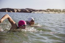 Aktive Schwimmerinnen am Tag auf See gegen Ufer — Stockfoto