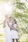 Наречена і подружка нареченої обіймаються в домашньому саду під час весільного прийому — стокове фото