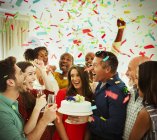 Familia entusiasta con pastel de cumpleaños lanzando confeti - foto de stock