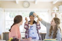 Three teenage girls playing with beanie in dining room — Stock Photo