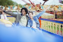 Cheerful couple on carousel in amusement park — Stock Photo
