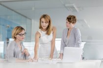 Female architects discussing blueprint at laptop in conference room meeting — Stock Photo
