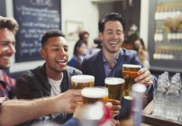 Чоловіки друзі тости пивні окуляри в барі — стокове фото