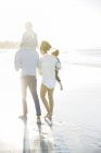 Семейная прогулка на пляже при солнечном свете — стоковое фото