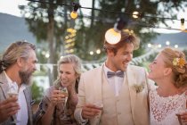 Pareja joven y sus invitados con flautas de champán durante la recepción de la boda en el jardín - foto de stock