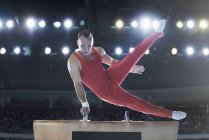 Male gymnast performing on pommel horse in arena — Stock Photo