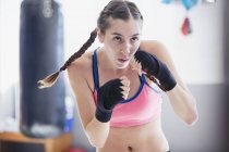 Décidée, jeune boxeuse robuste shadowboxing dans la salle de gym — Photo de stock