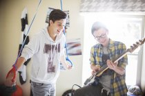 Двоє хлопчиків-підлітків розважаються і грають на електрогітарі в кімнаті — стокове фото