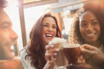 Enthusiastic friends toasting coffee cups at cafe — Stock Photo