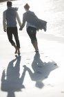 Jeune couple tenant la main et marchant sur la plage — Photo de stock