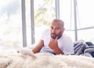 Portrait serious handsome man using digital tablet on bed — Stock Photo
